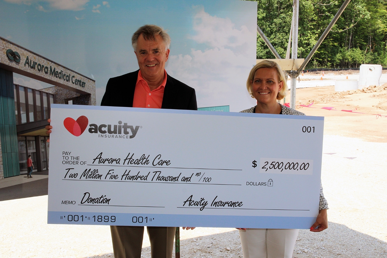 Ben Salzmann, Acuity President and CEO, presents a $2.5 million donation to Carrie Killoran, Executive Vice President with Advocate Aurora Health.
